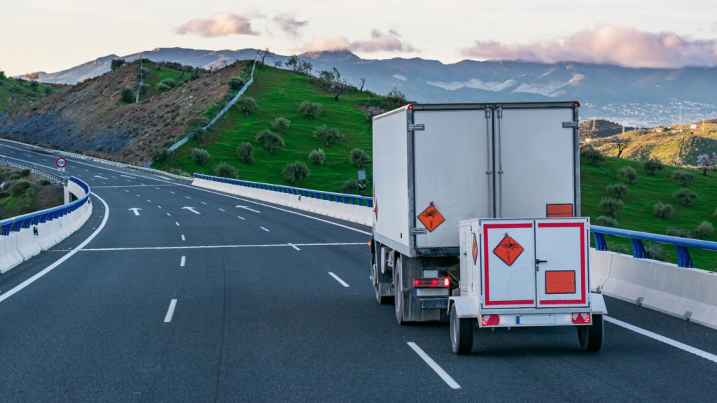 Ein Gefahrengut-Transporter fährt auch einer Straße zwischen Bergen